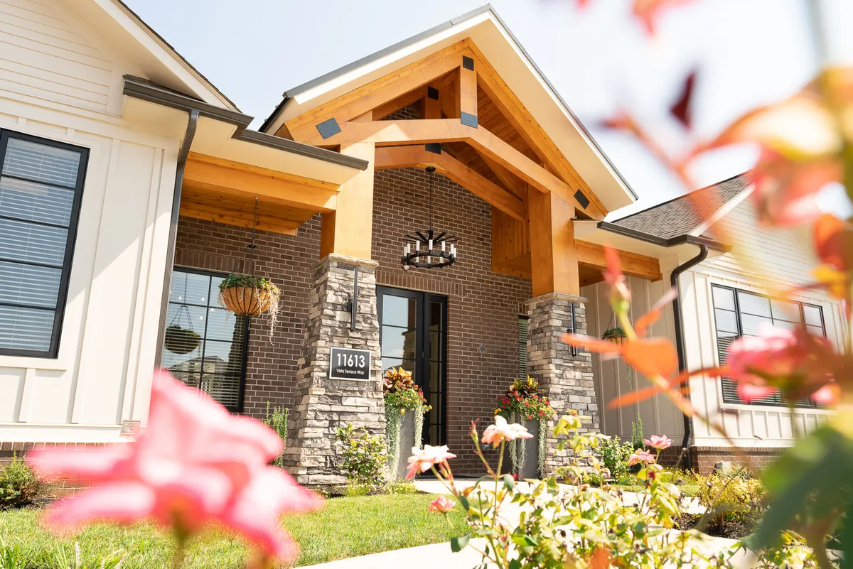This image captures the inviting entranceway of the property, featuring striking wooden beams, textured stonework, and neatly maintained landscaping. The scene hints at a welcoming, upscale ambiance and provides a sense of arrival that aligns with the idea of starting a romantic city adventure from a stylish home base.