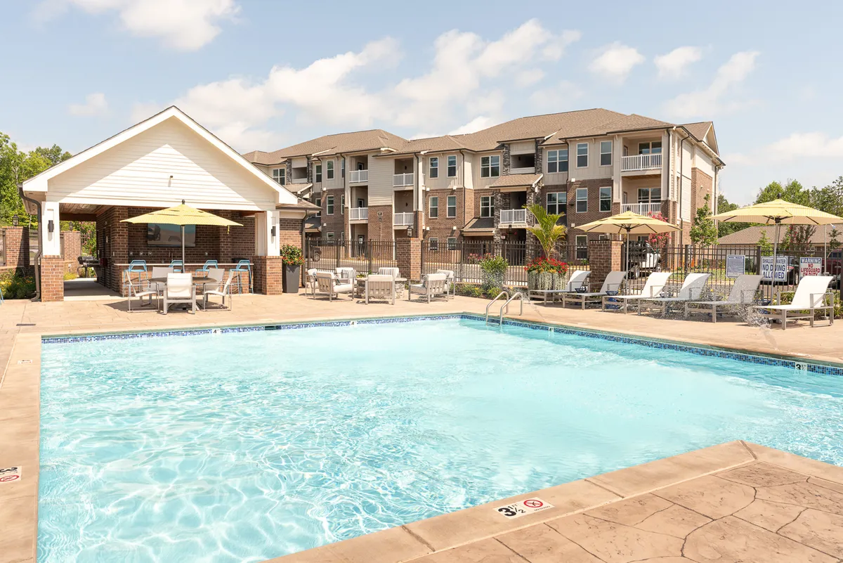 This image showcases a vibrant pool area with cabana seating, lounge chairs, and umbrellas set against the backdrop of modern apartment buildings. The scene is lively yet relaxed, suggesting opportunities for outdoor leisure, socializing, or quiet couple time away from the city's hustle.