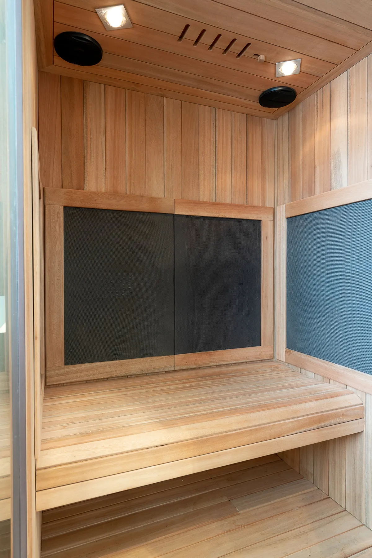 An inviting wellness space with wooden benches, sleek wood paneling, and subtle, soothing lighting. The mood is serene, ideal for relaxation or post-workout recovery.