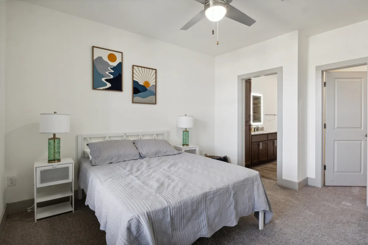 A serene bedroom with a stylish bed, cozy bedding, soothing artwork, and elegant light fixtures. Soft lighting enhances the calm, restful atmosphere ideal for unwinding after a busy day.